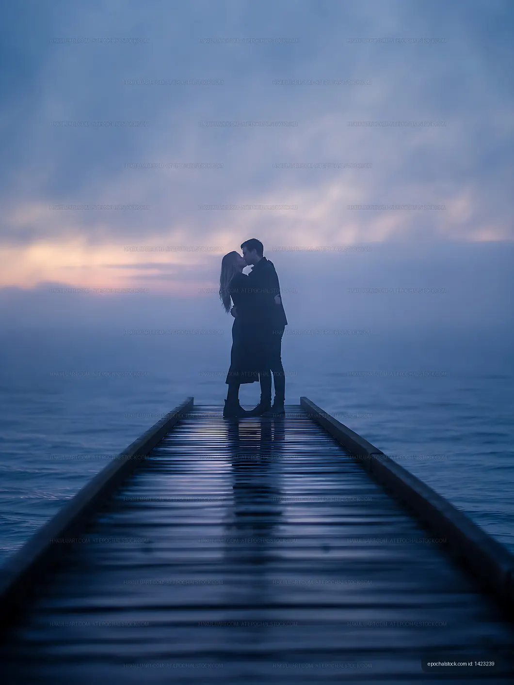 Couple kissing on a wooden dock during foggy sunset
