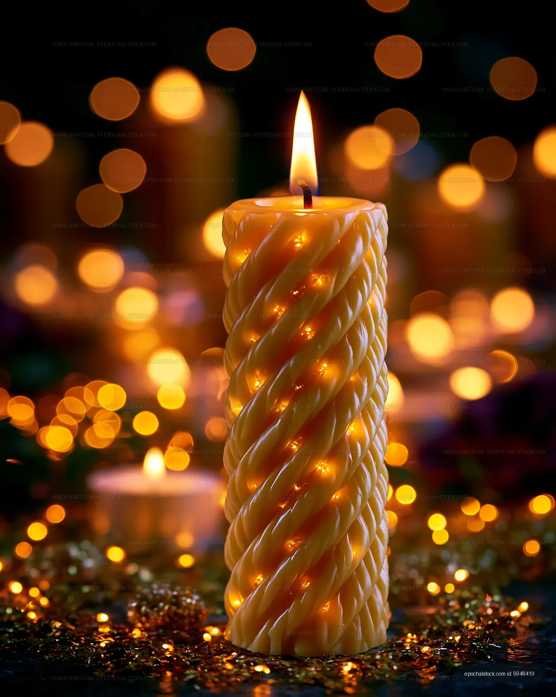 Twisted yellow candle lit against glowing bokeh lights