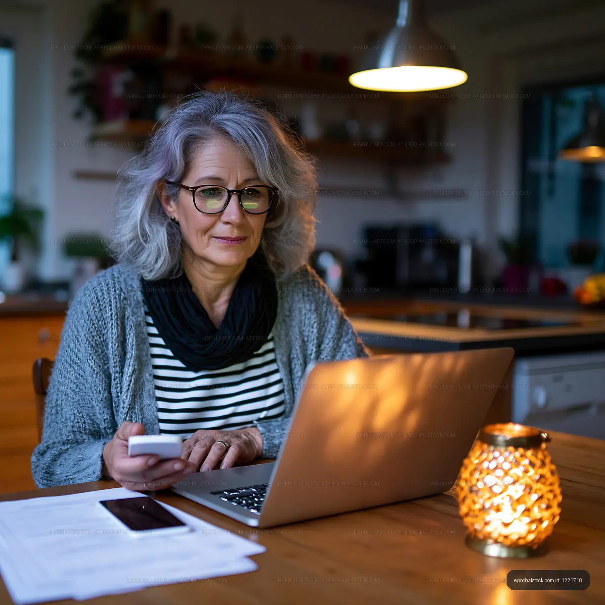 Woman using laptop at home with a phone and candlelight