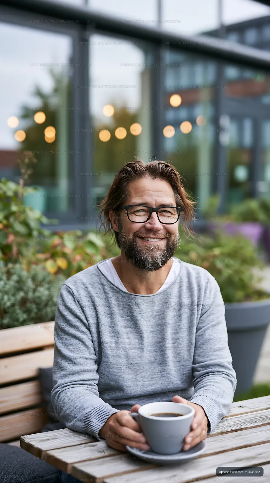 Man enjoying coffee at outdoor cafe with green plants