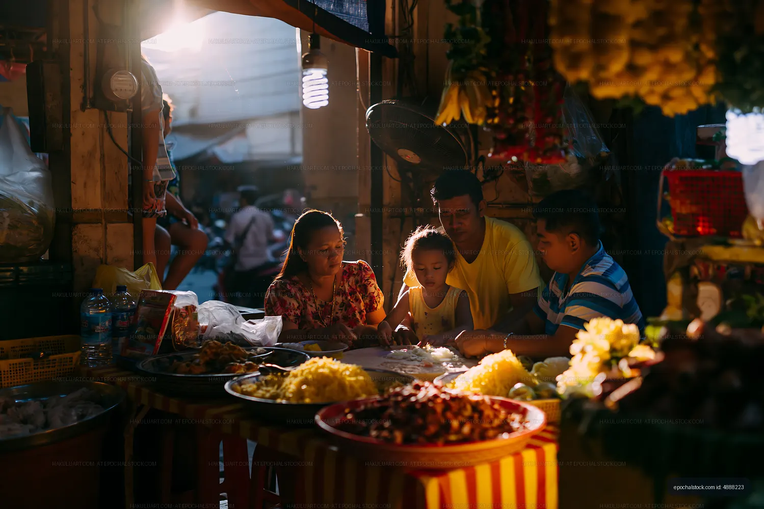 Family gathered around a table at a local market in the evening