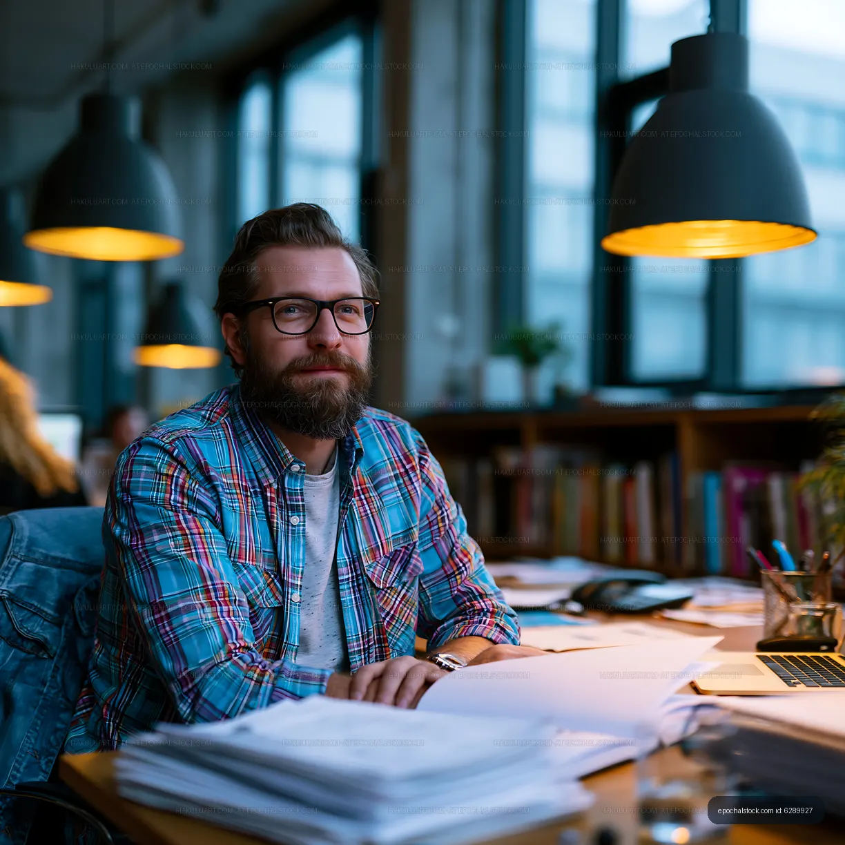 Man working at a desk in an office with books and papers
