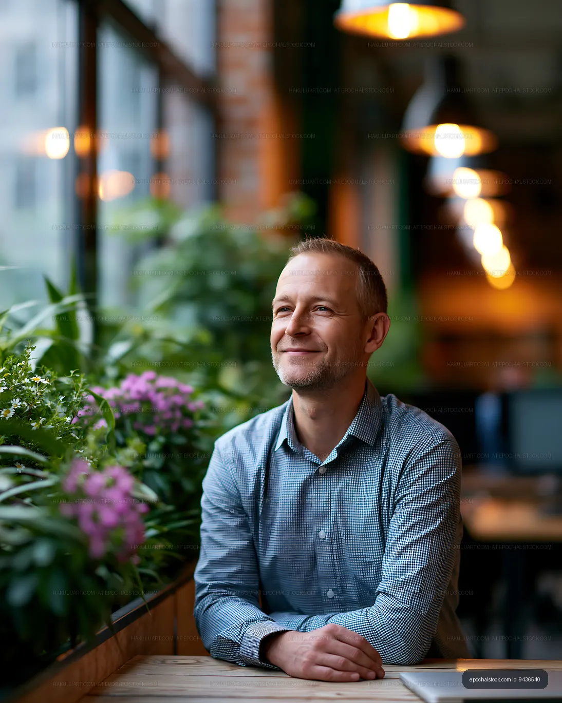 Man sitting by a window in a cafe with plants and flowers