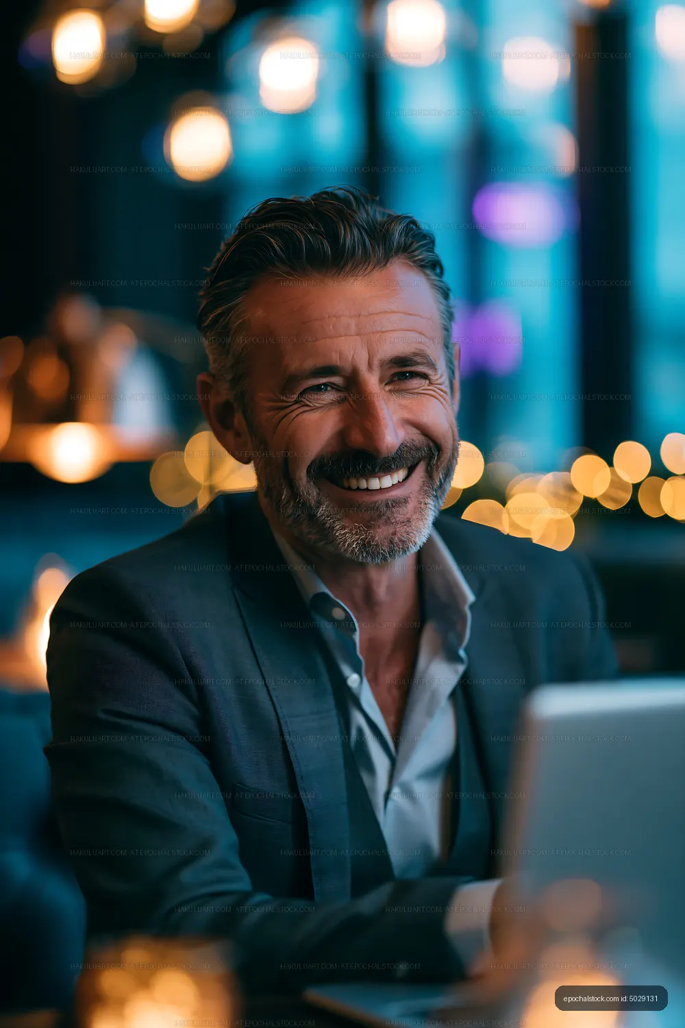 Man smiling in a cafe at night with warm lighting around him