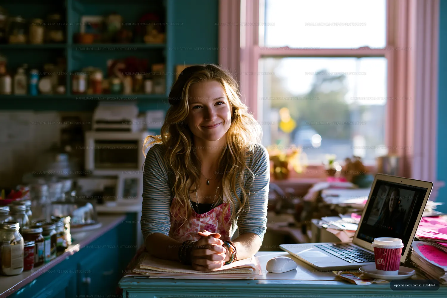 Young woman smiling at kitchen table with laptop and coffee cup