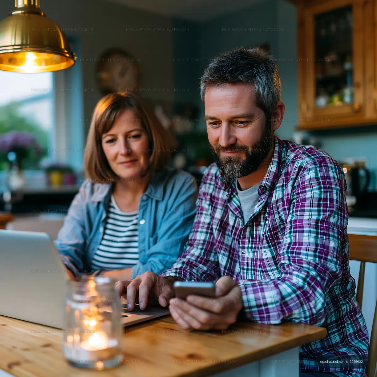 Couple working on a laptop and smartphone at home in evening light