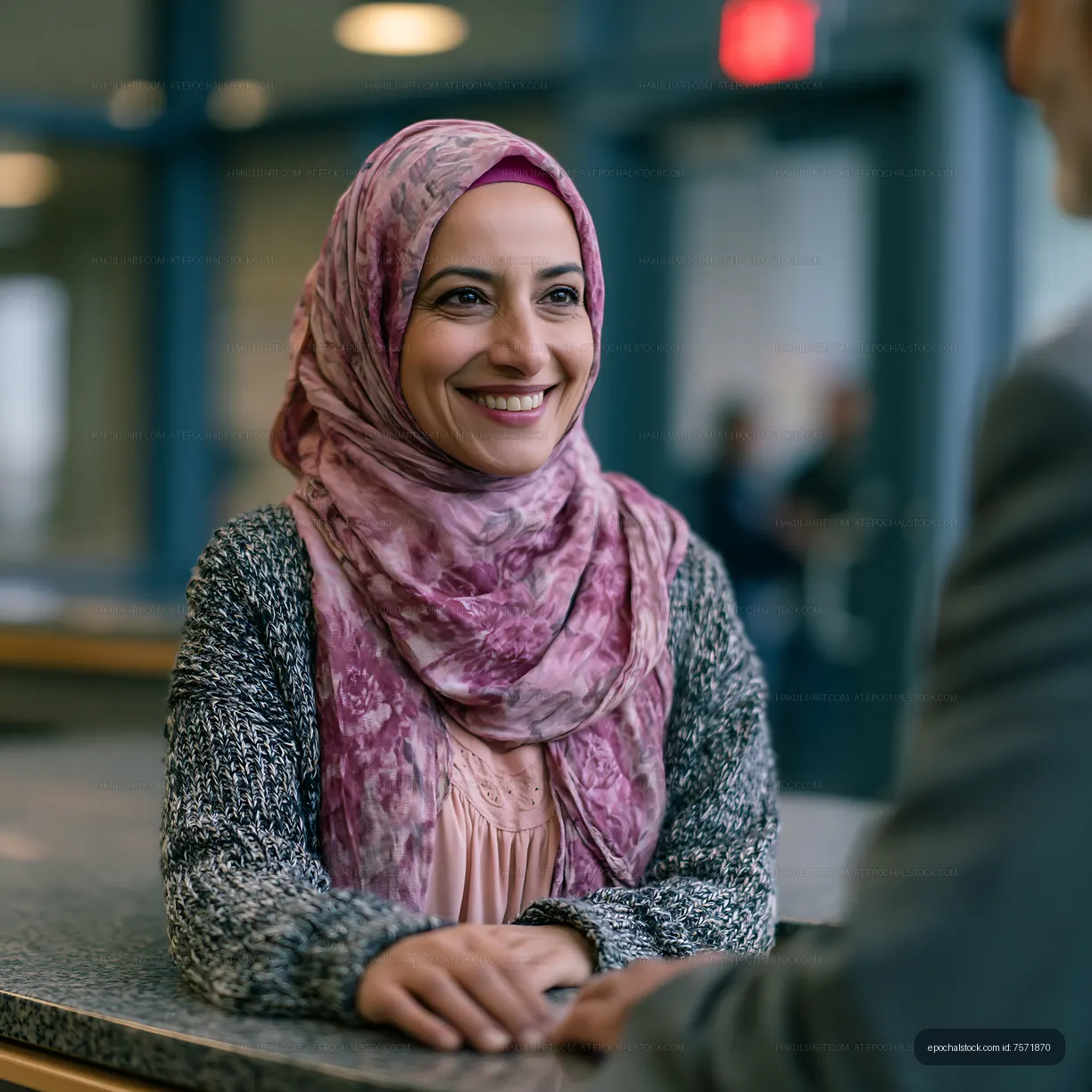 Woman in headscarf smiling during conversation in office setting