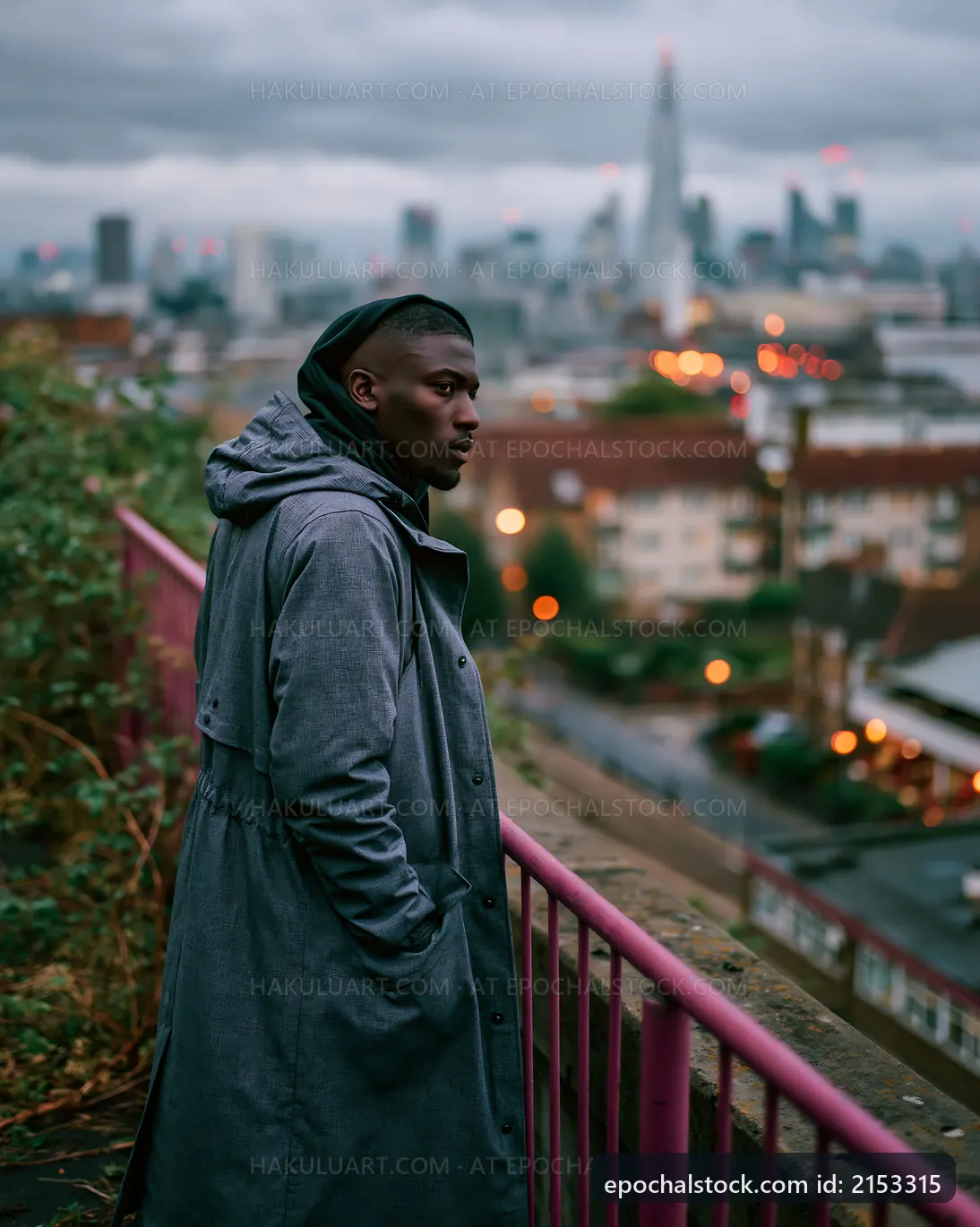 Man in gray coat looking over city skyline at dusk