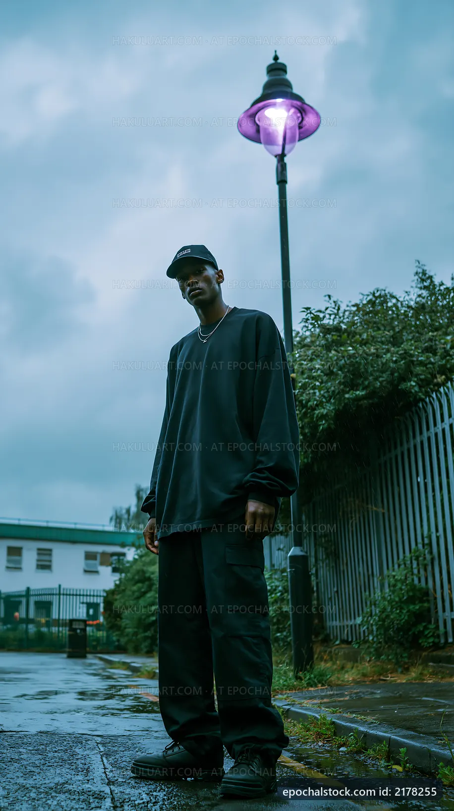Man standing under a lamp post on a rainy street
