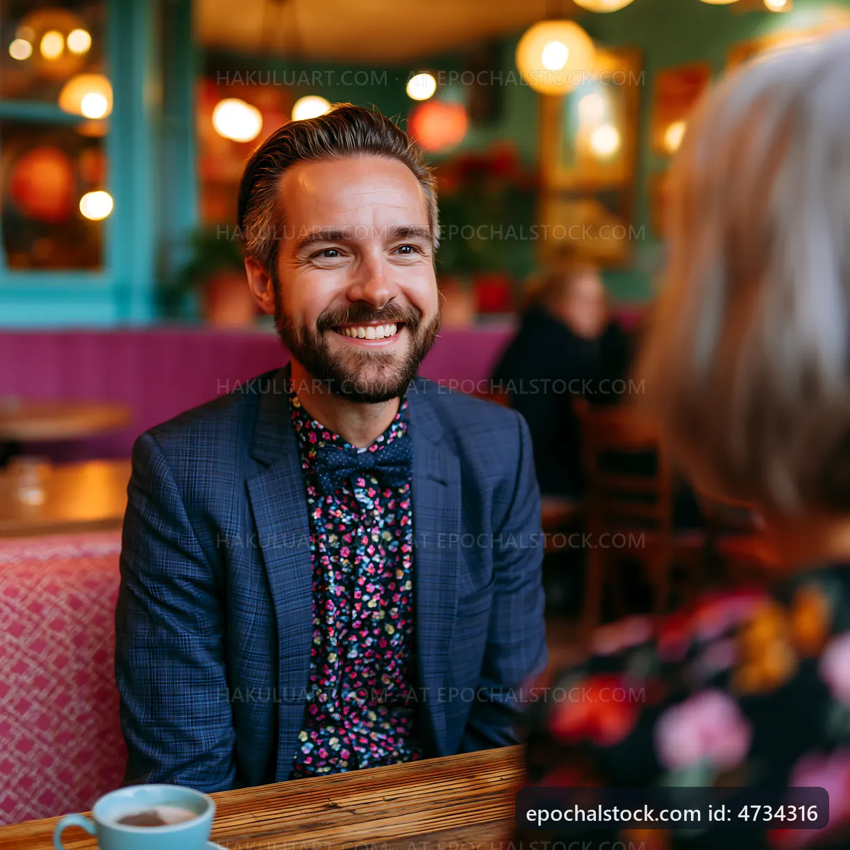 Man smiles while talking to a woman in a cafe setting