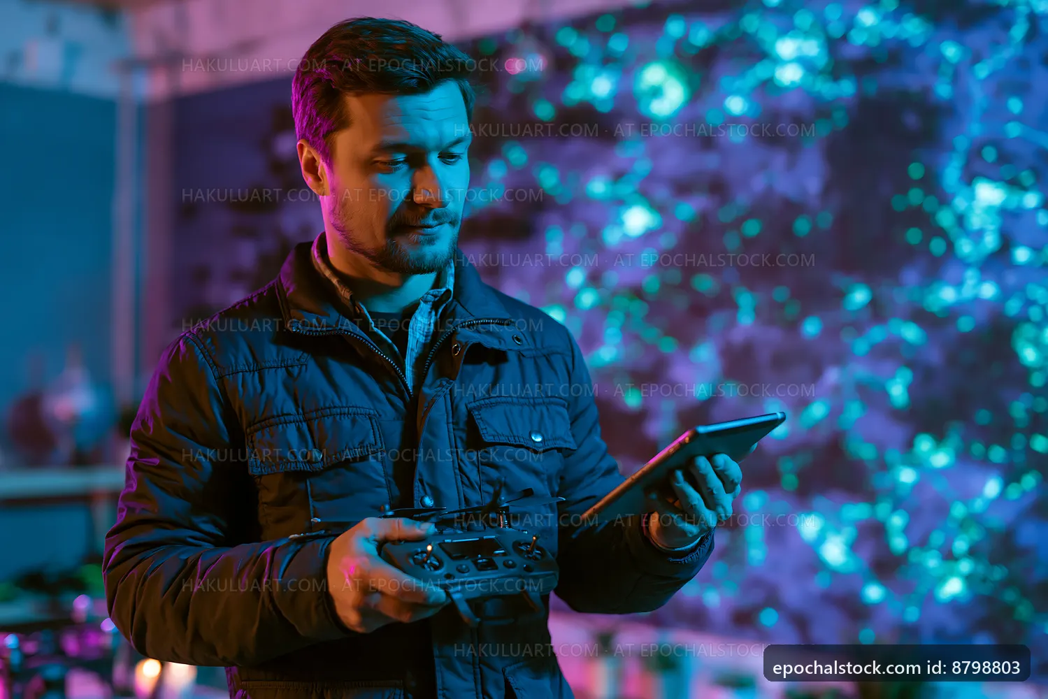 Man operating drone controller in colorful lighting