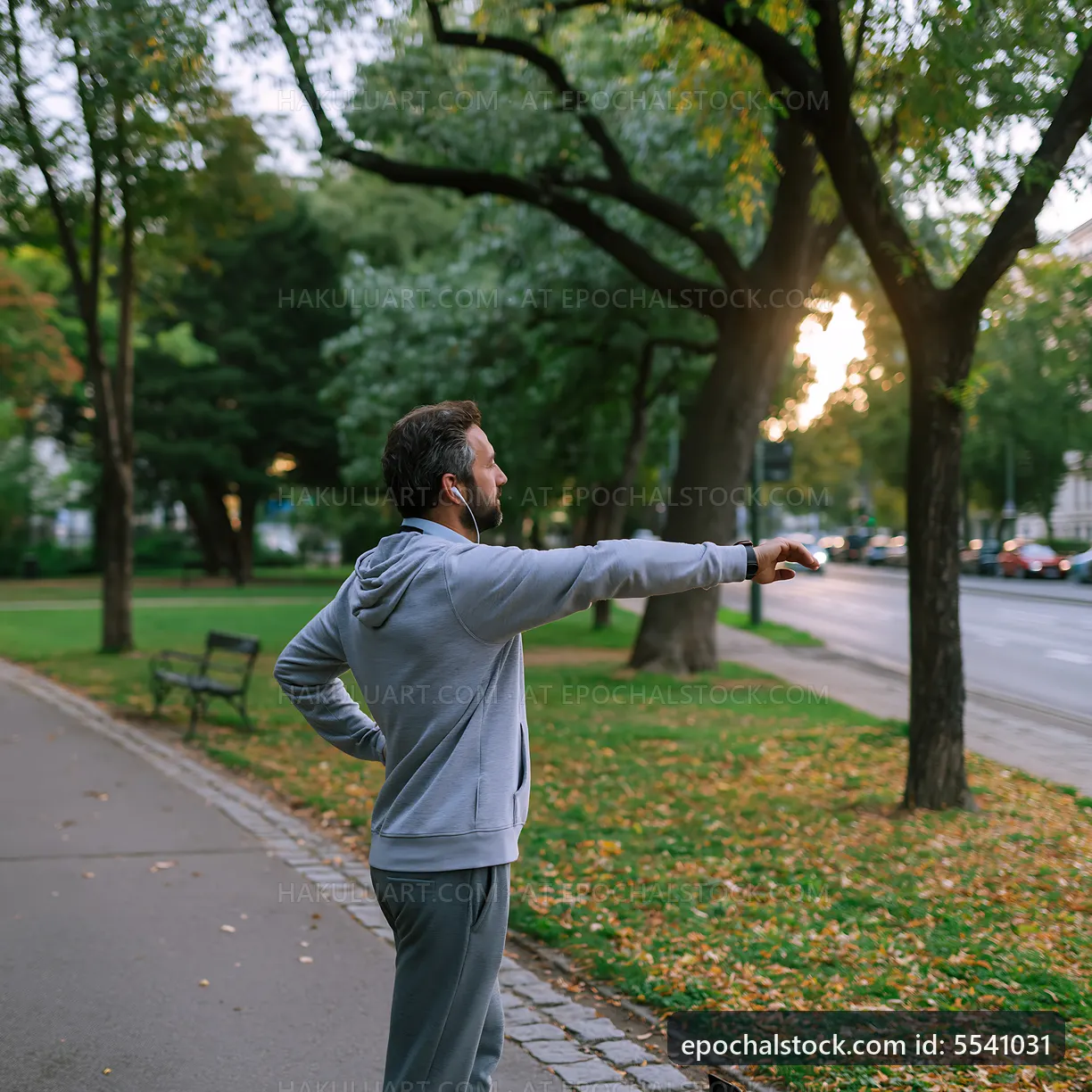 Man stretches in park during sunset while listening to music