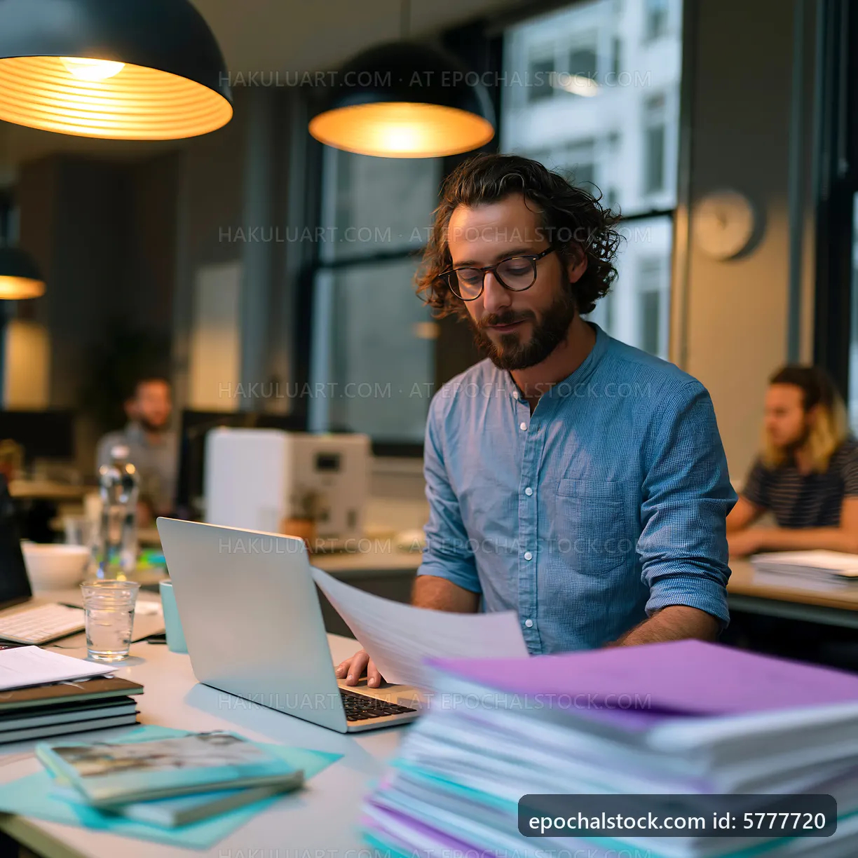 Man working at a desk in a busy office during the day