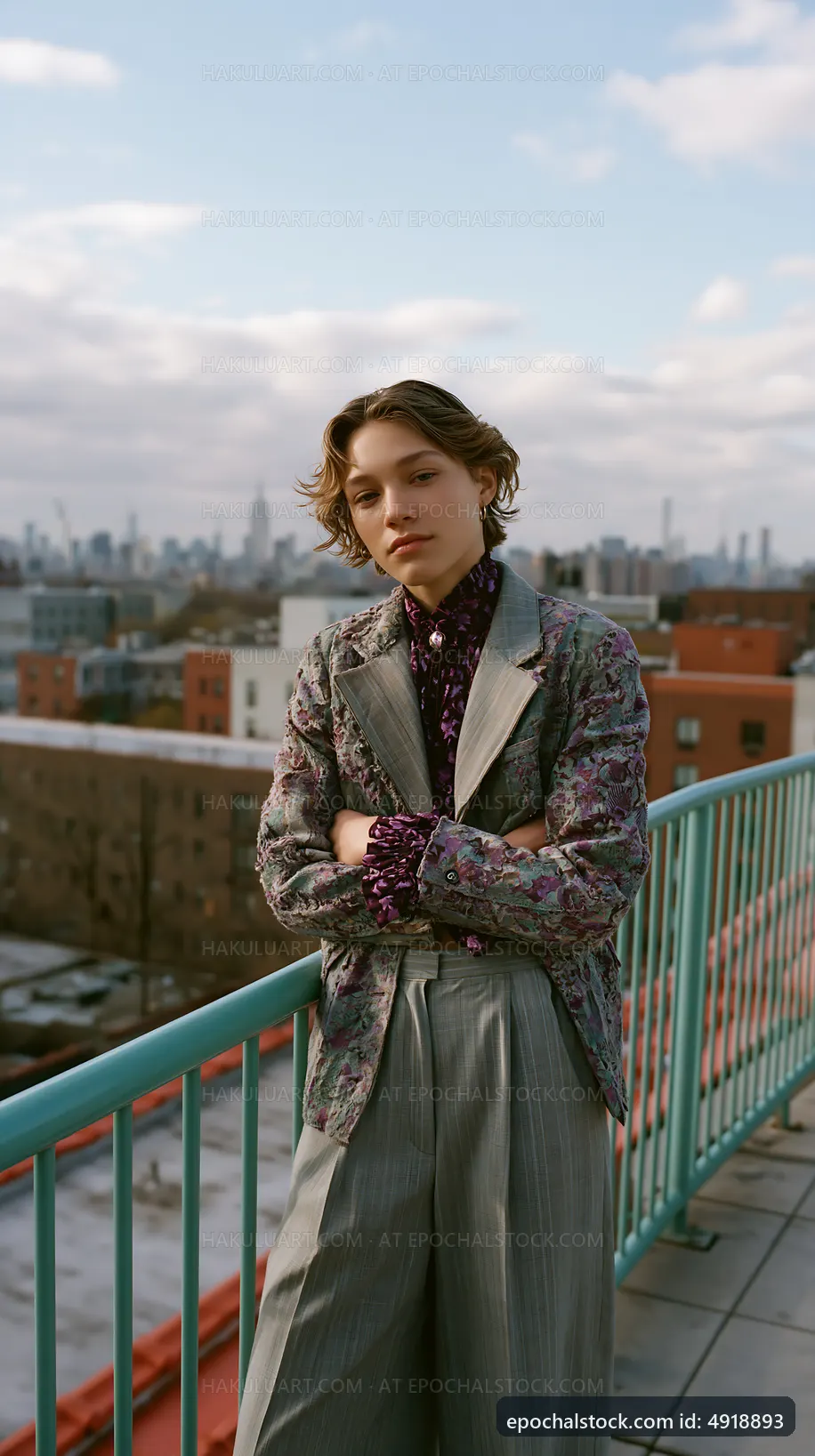 Young model poses on rooftop with city skyline in background