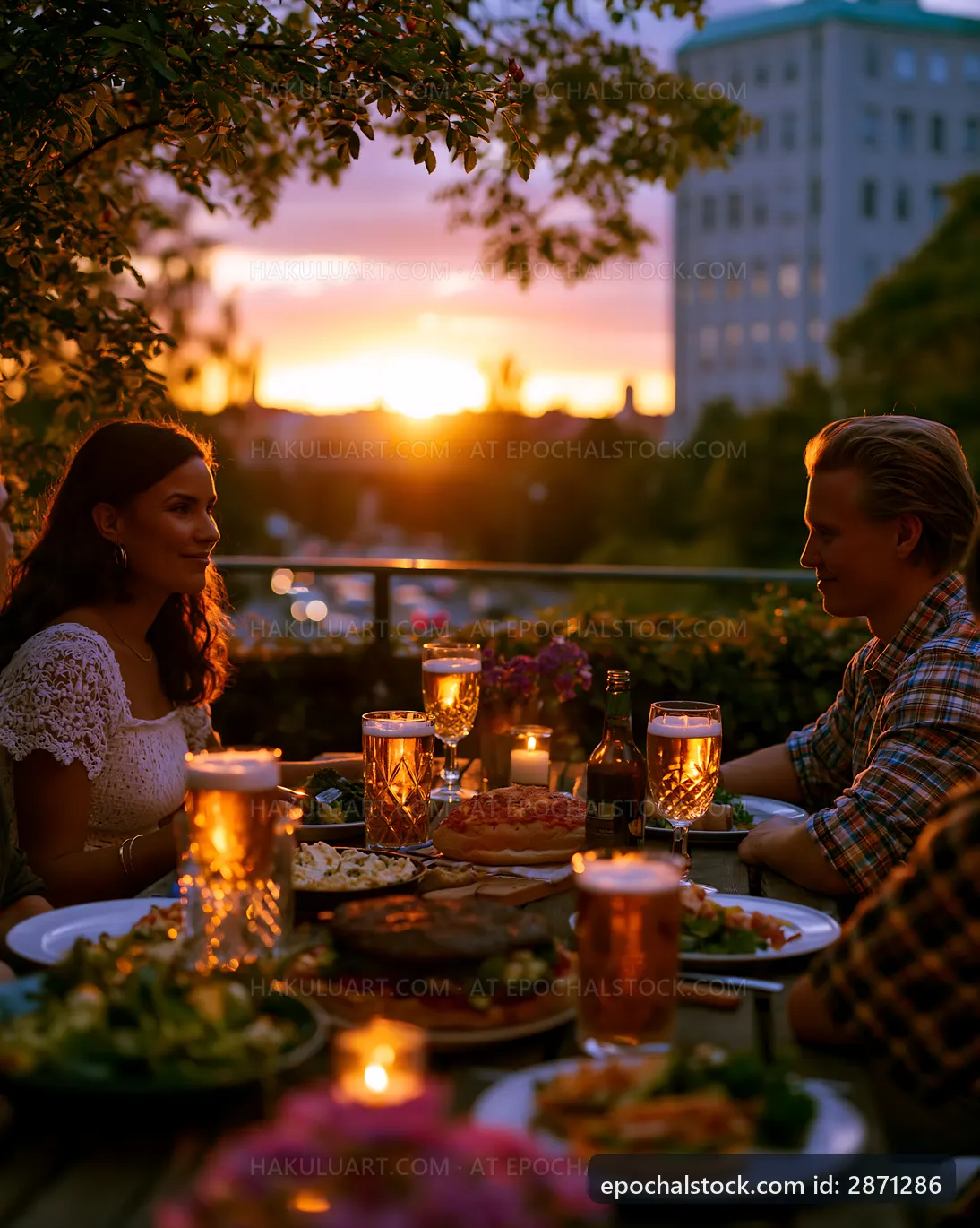 Couple enjoying outdoor dinner at sunset with drinks and food