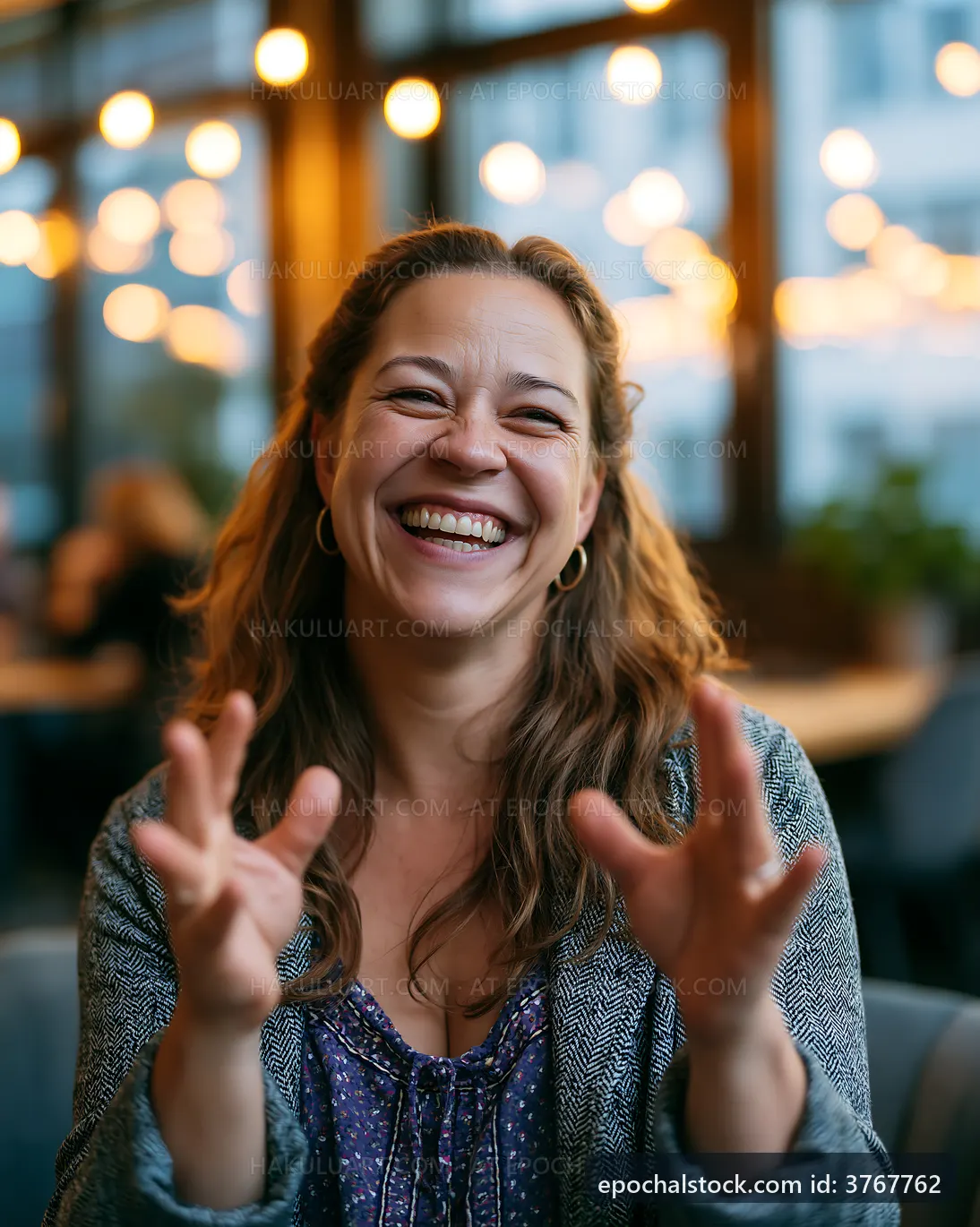 Woman laughing indoors at a cafe with warm lighting