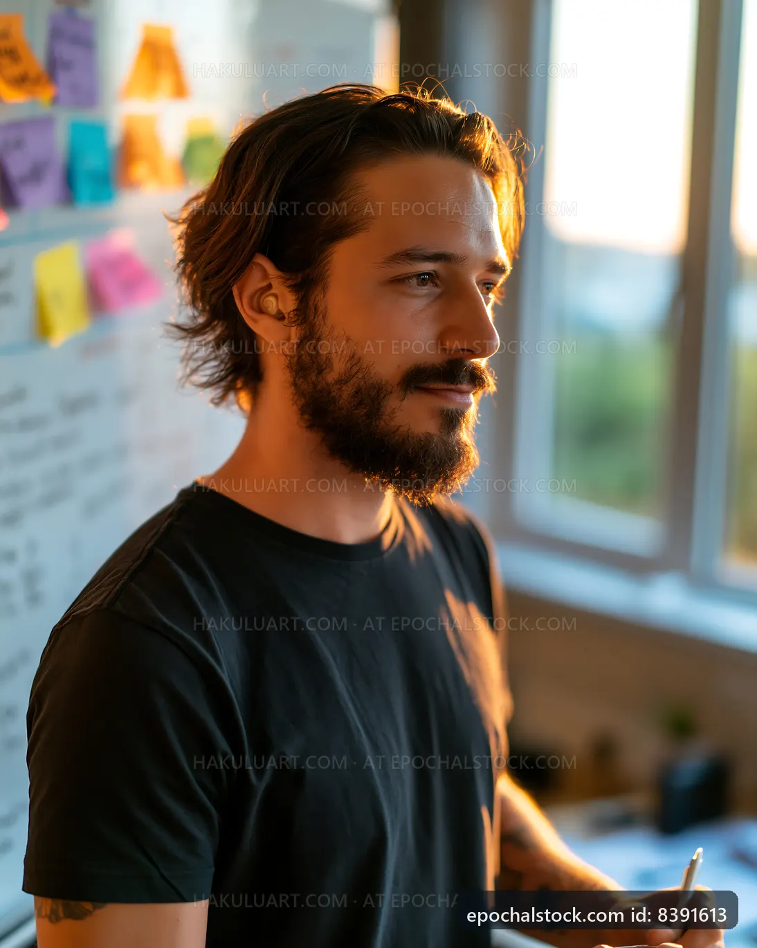 Young man working in an office with sticky notes on a board