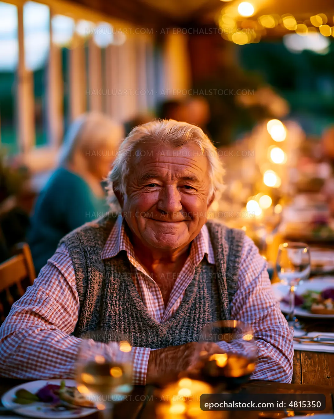 Elderly man smiling at outdoor dinner with friends in evening light