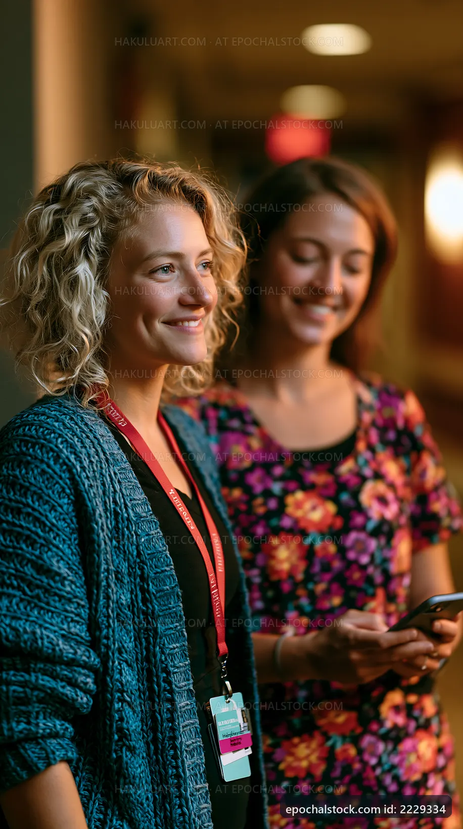 Two women smiling and standing together in a hallway