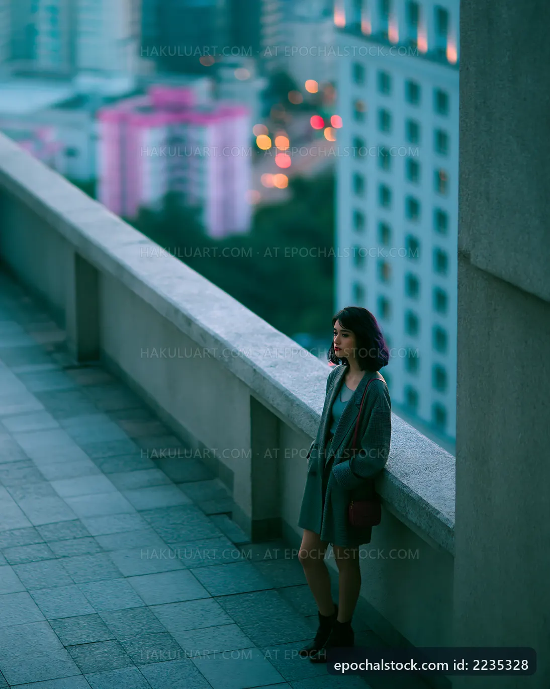 Woman standing on a rooftop at dusk in a cityscape
