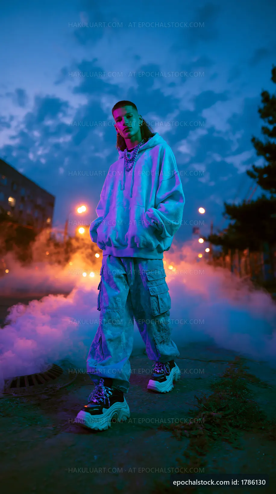 Young person in streetwear standing in fog at dusk