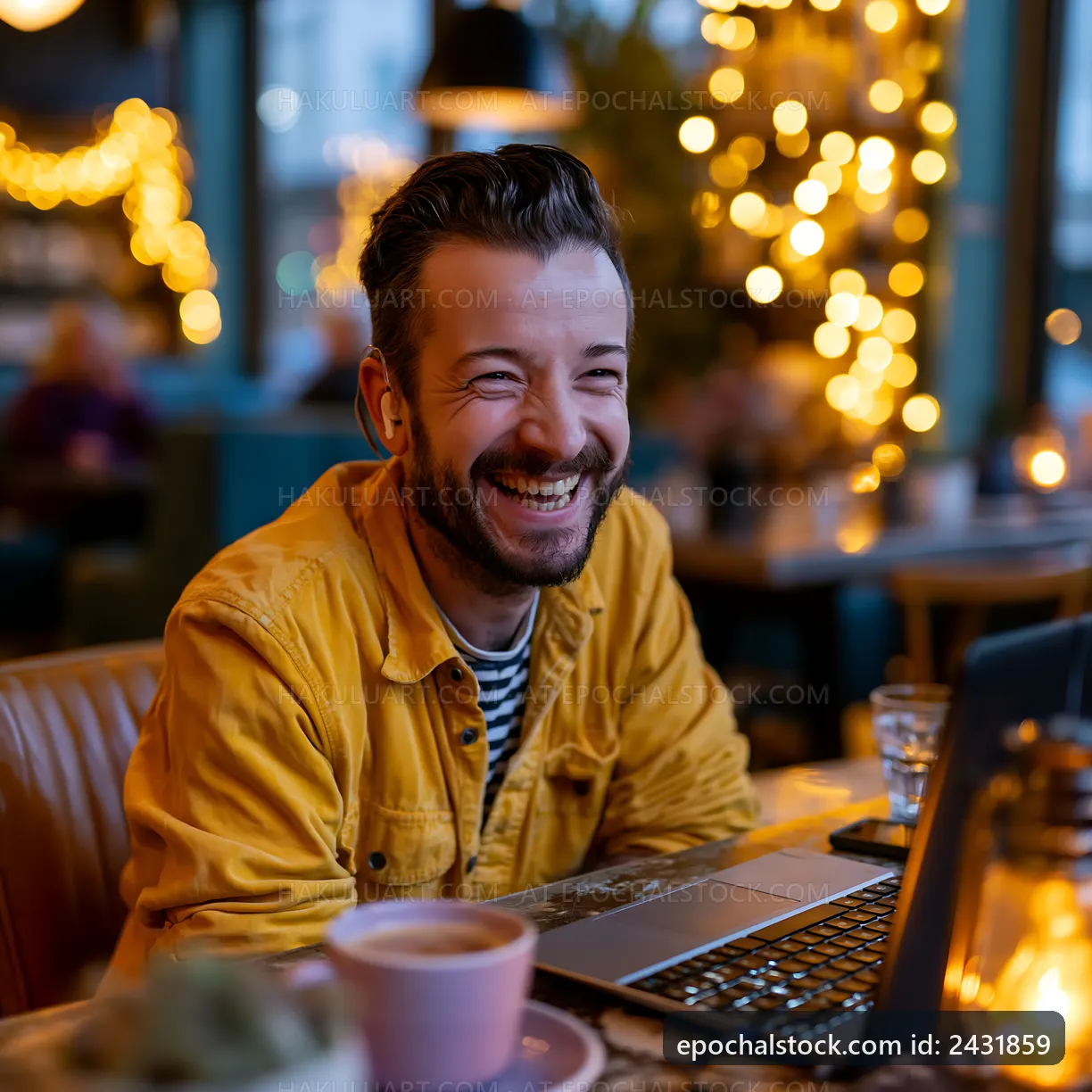 Man smiles while working on a laptop in a cozy cafe
