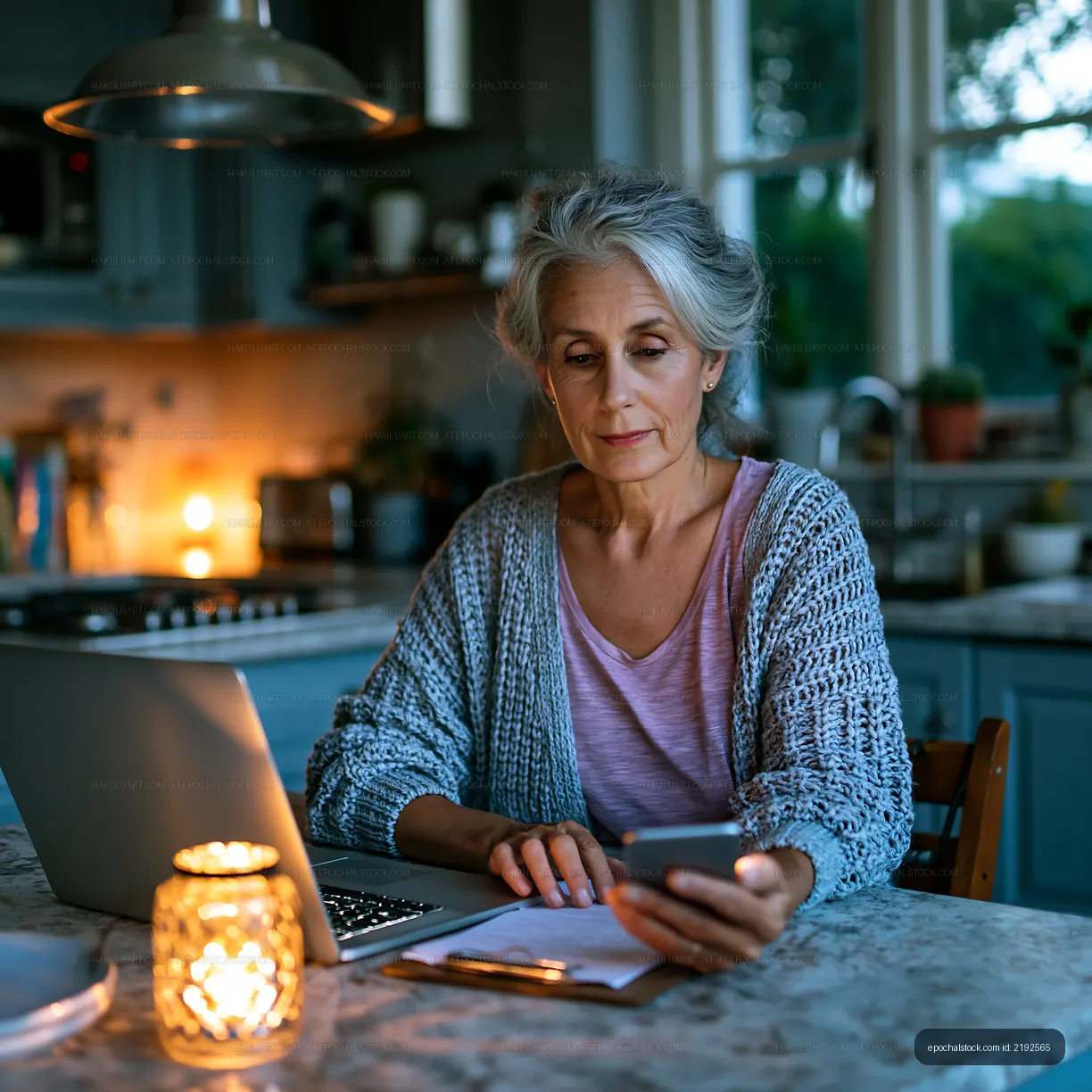 Woman sitting at a kitchen table using a smartphone in the evening