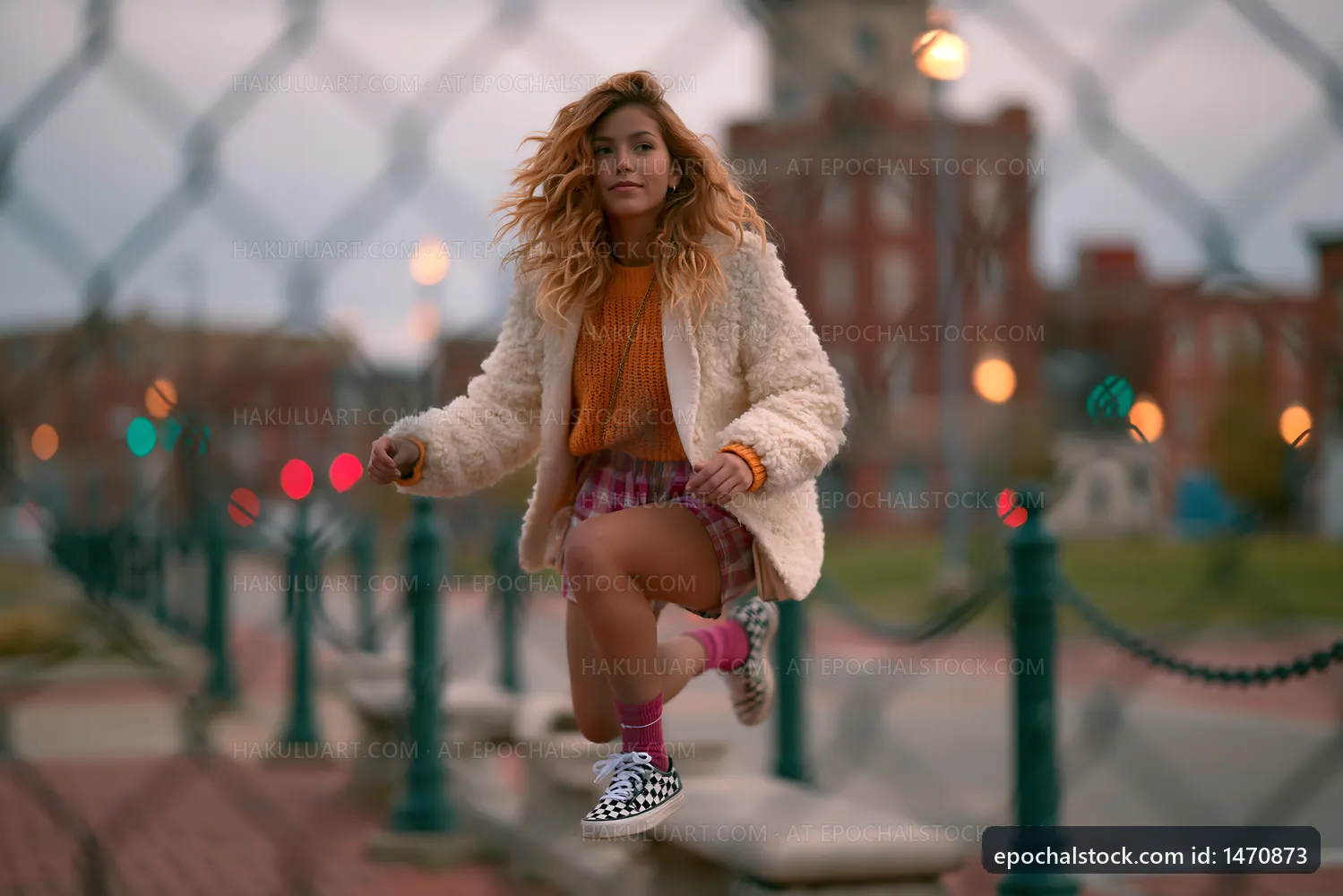 Woman jumping near a fence at sunset in a park