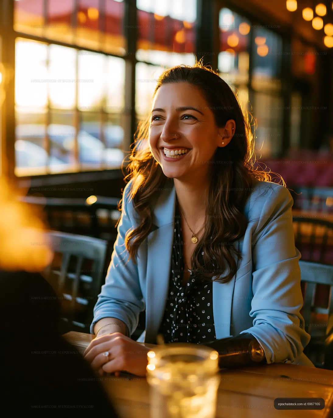Woman smiling at a table during sunset in a cozy restaurant