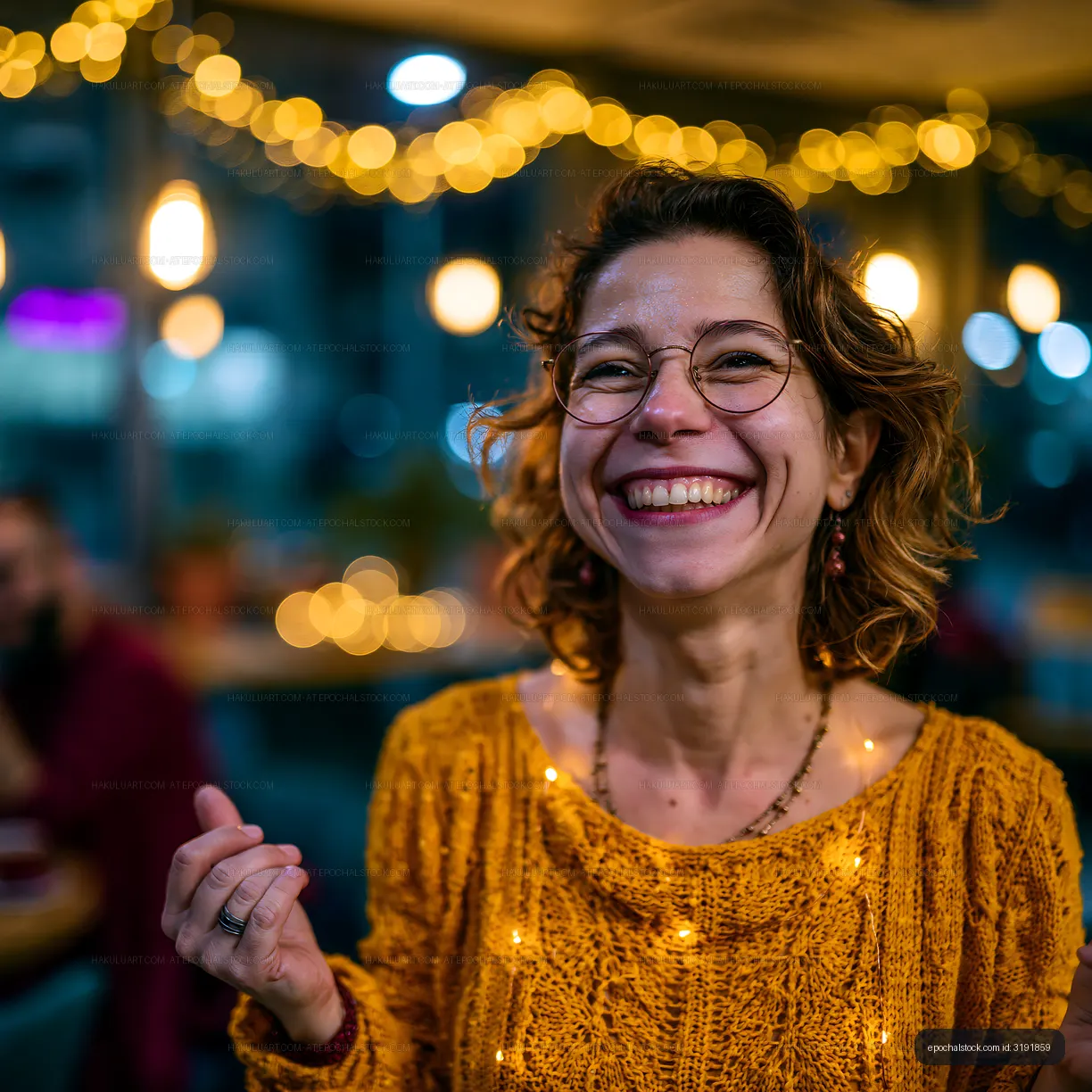 Woman smiling in warm light with festive decorations in café