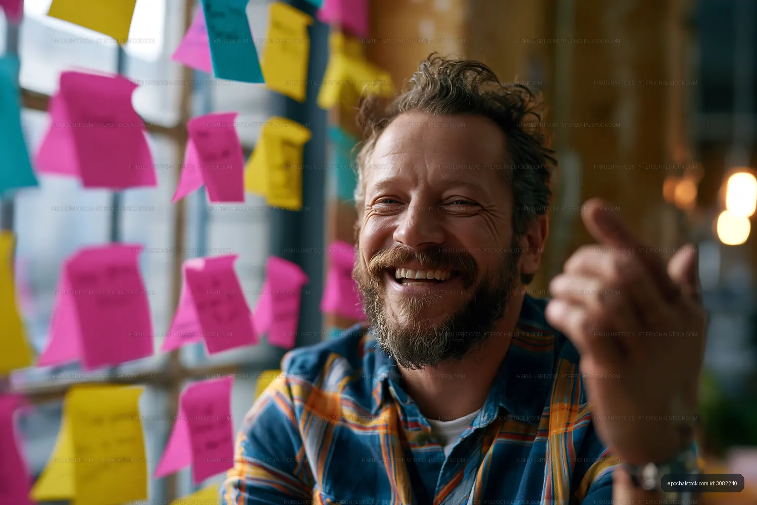 Man smiling by a window with colorful sticky notes on the wall