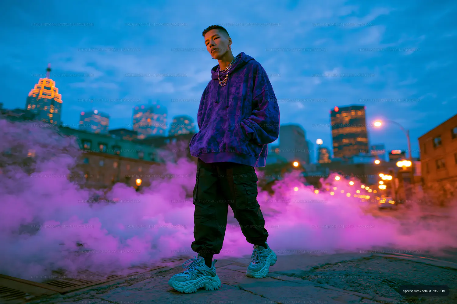 Man in purple hoodie stands in foggy city street at dusk