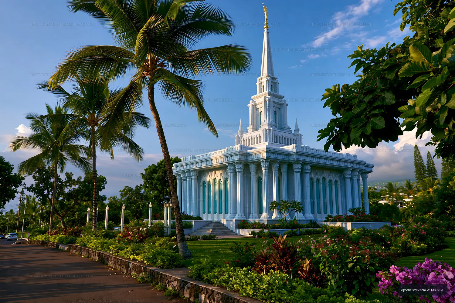 White temple with tall spire surrounded by green plants and palm trees