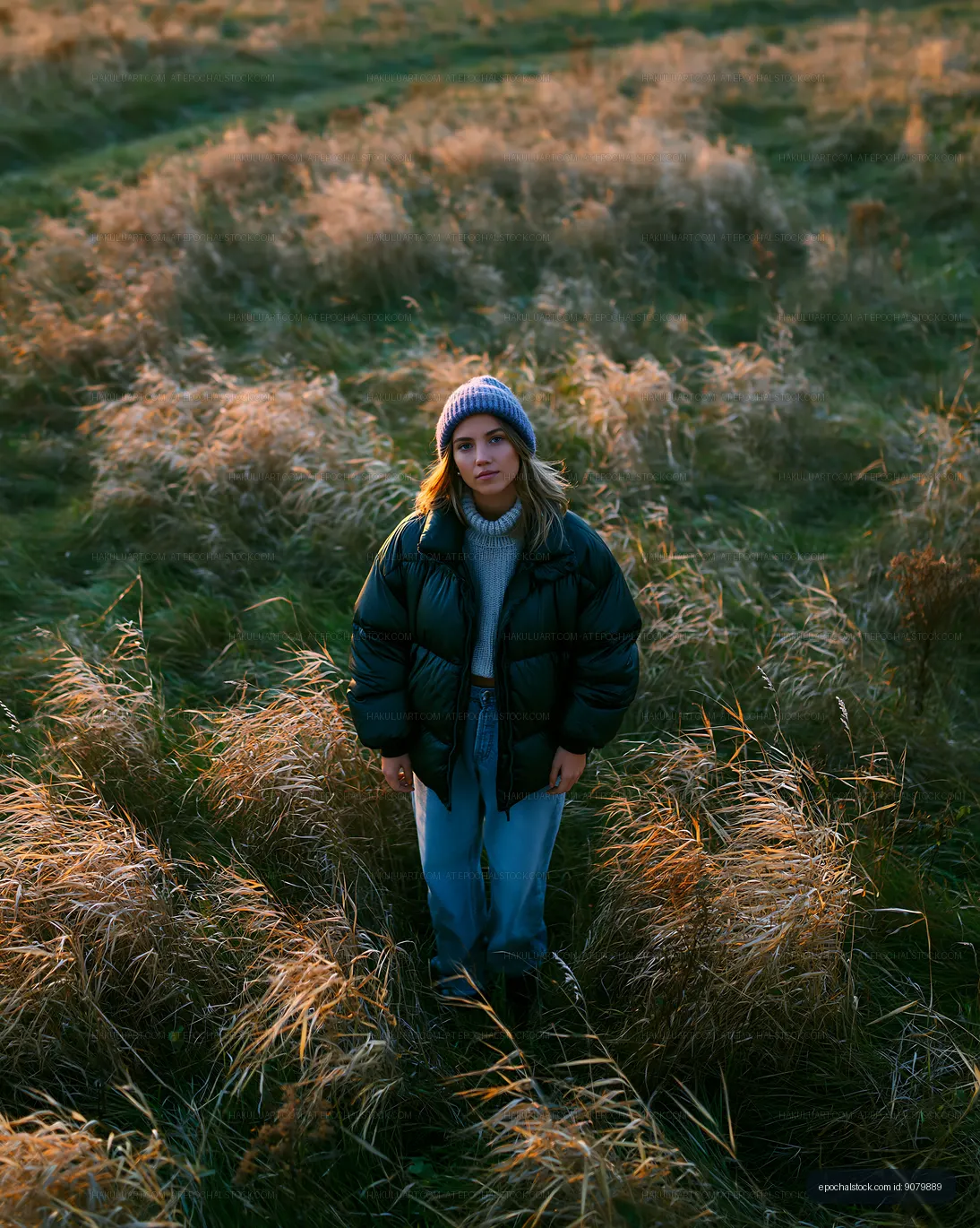 Woman standing in tall grass field during sunset