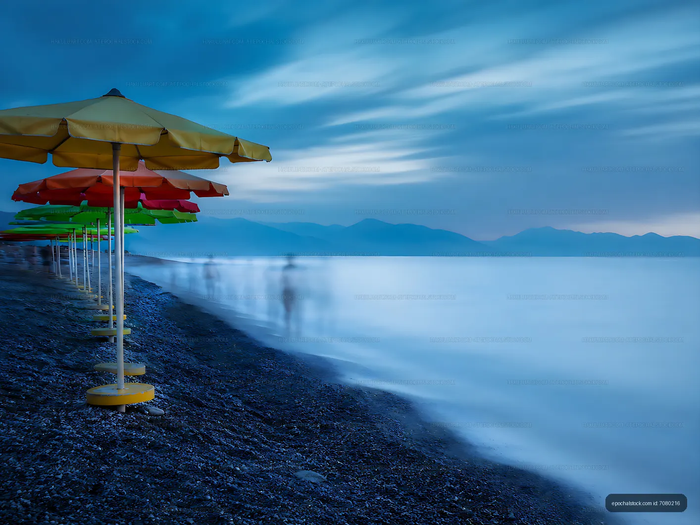 Beach with colorful umbrellas under a blue twilight sky