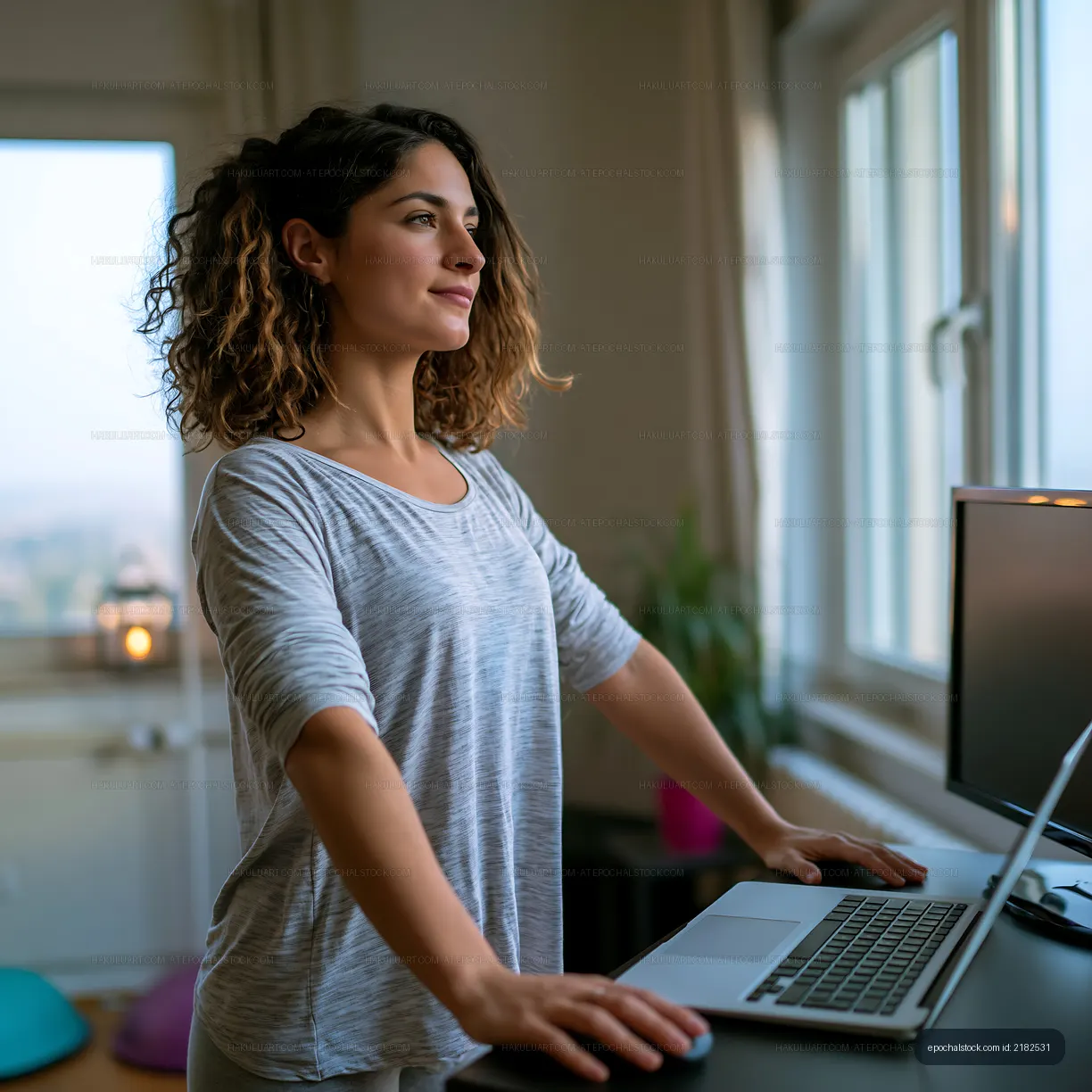 Woman standing by desk using laptop in a bright room