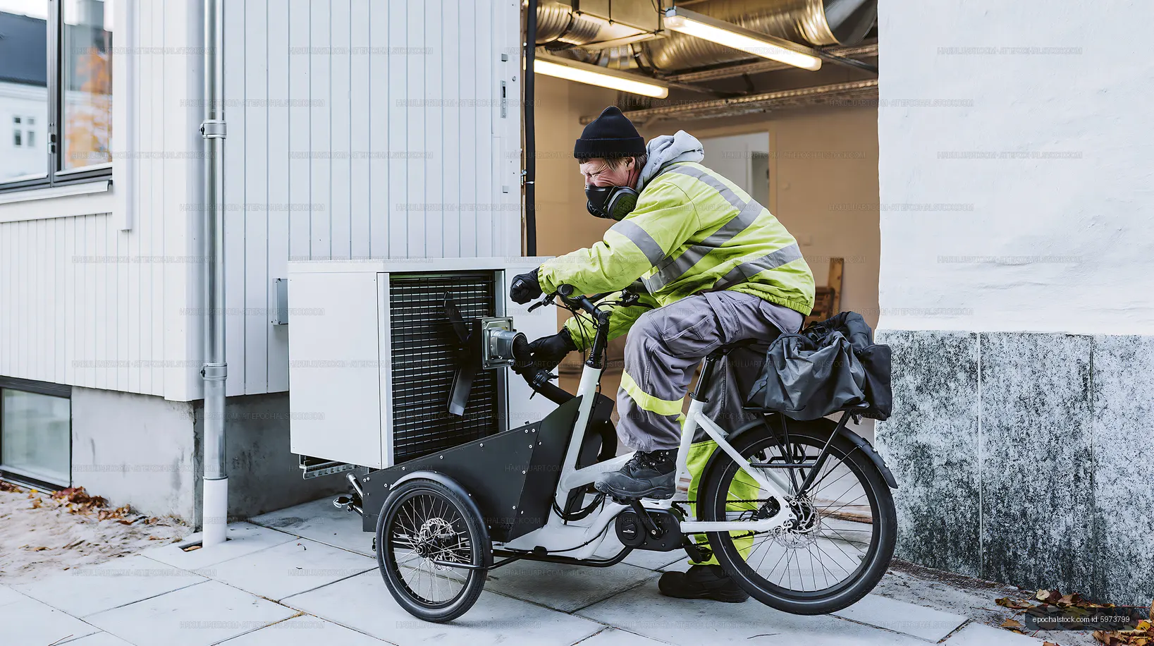 Delivery worker using cargo bike with portable cooler outside building