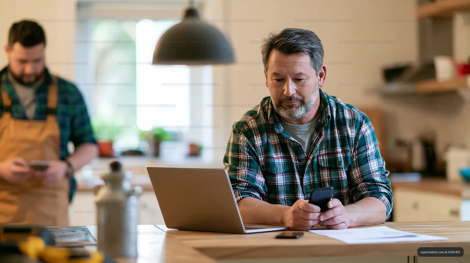 Man using laptop and phone in home kitchen