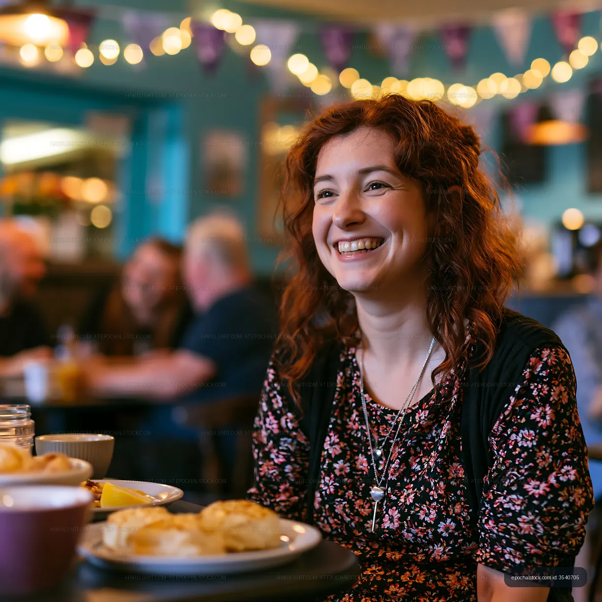 Woman smiling at a cafe table with food and guests in background