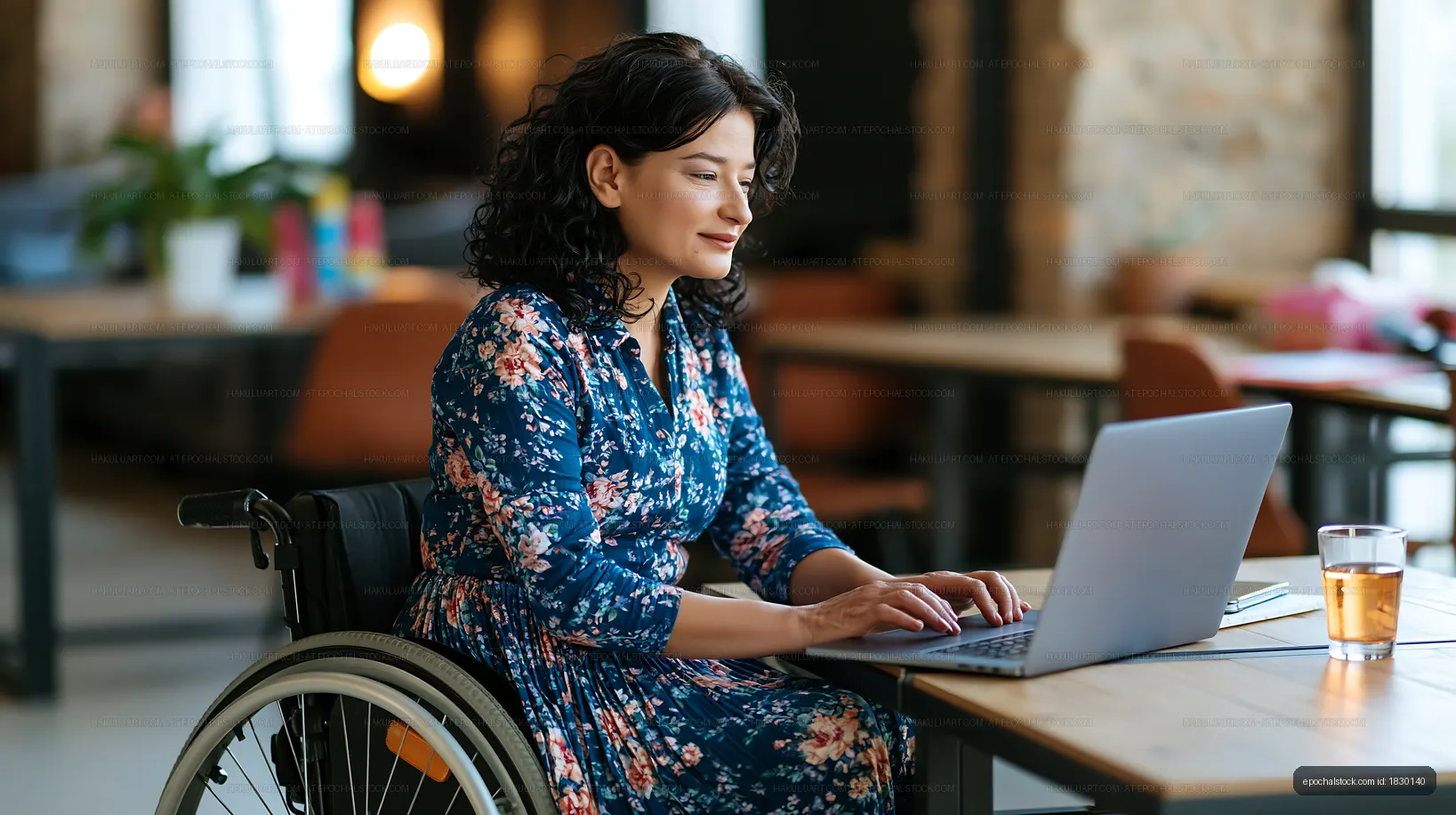 Woman in wheelchair working on laptop in a modern workspace