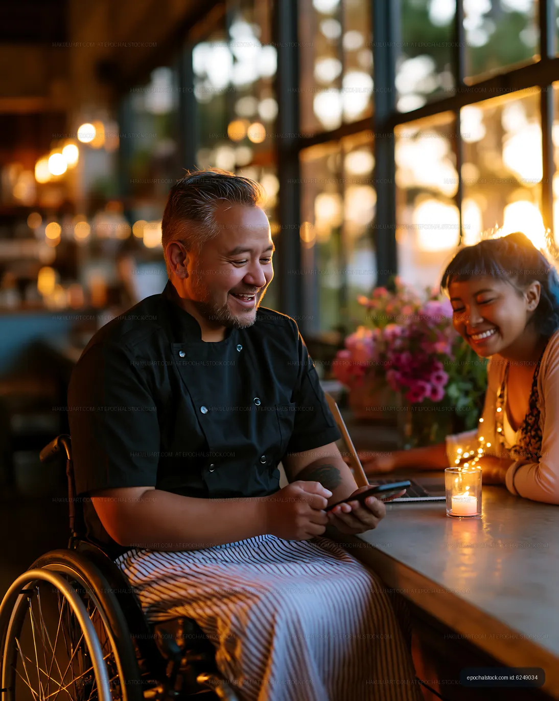 Chef in a wheelchair shares a laugh with a woman at sunset