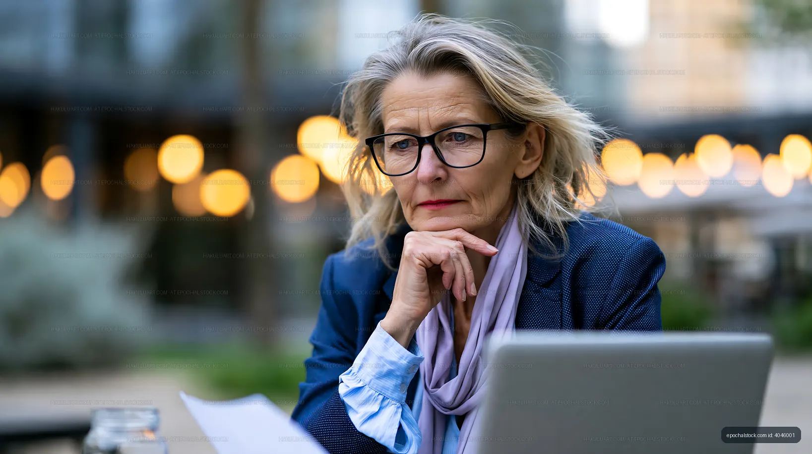 Woman working outdoors with laptop in cafe setting