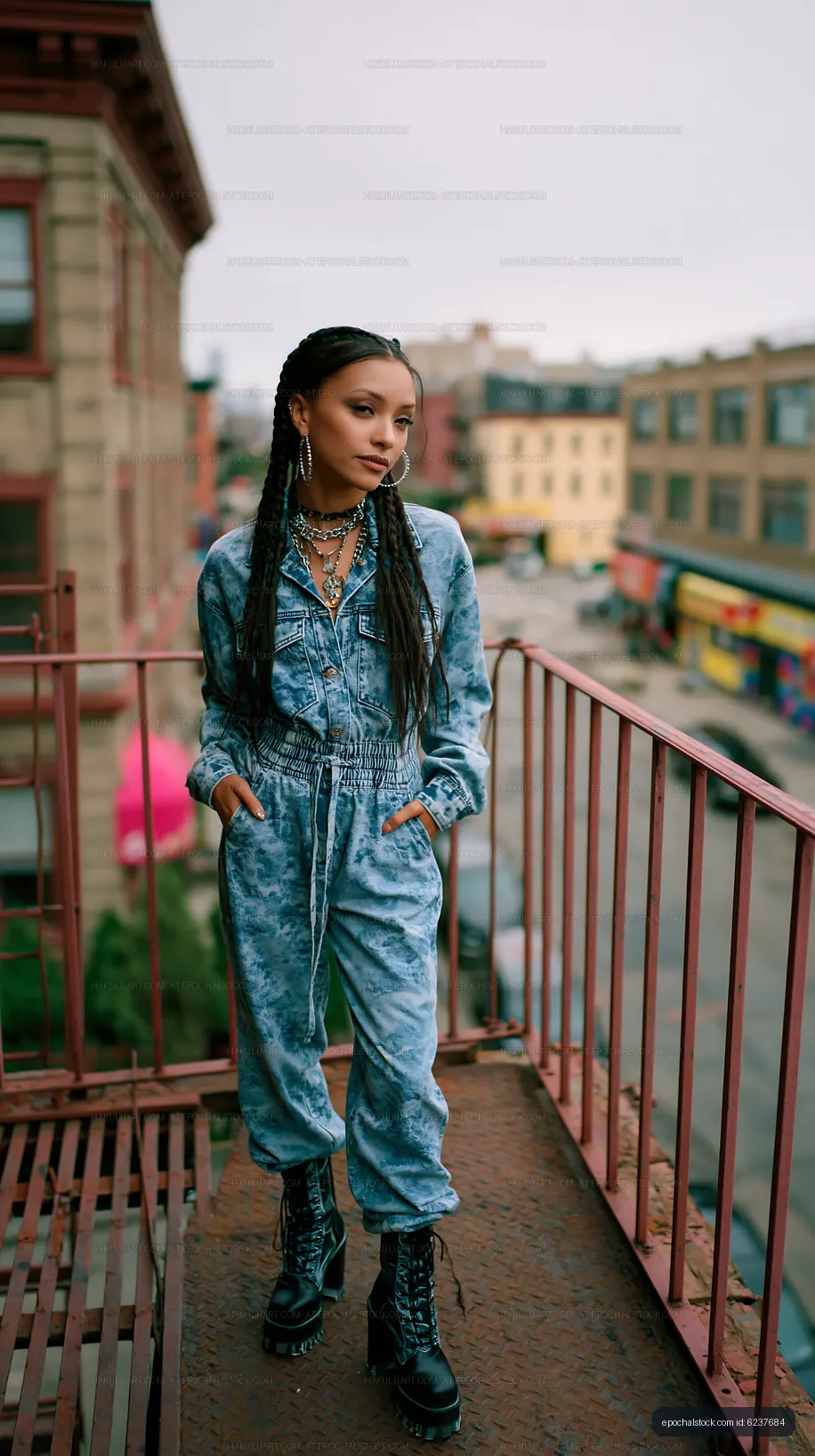 Woman in denim outfit stands on balcony in urban setting
