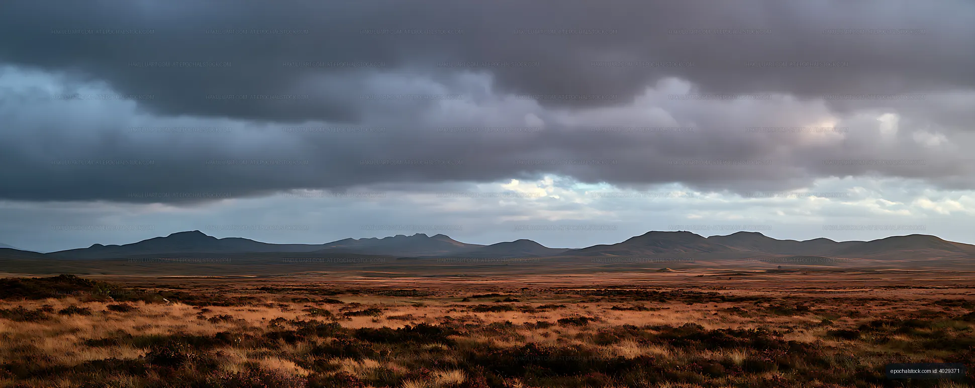 Dramatic storm clouds over a mountain grassland panorama