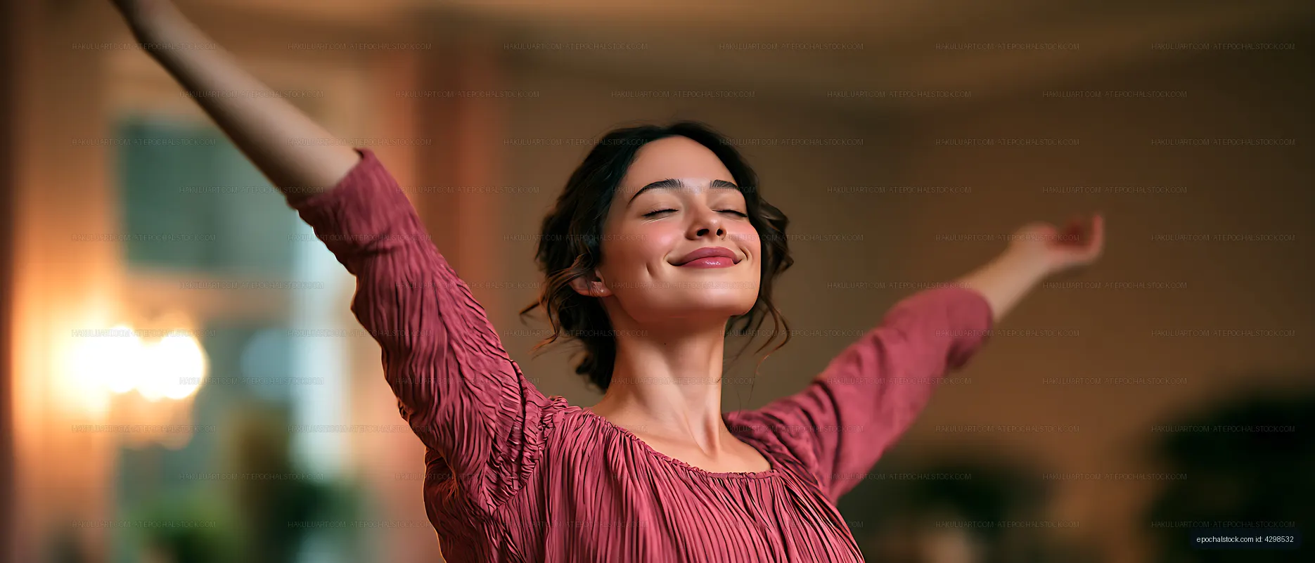 Smiling woman raising her arms in a warmly lit room