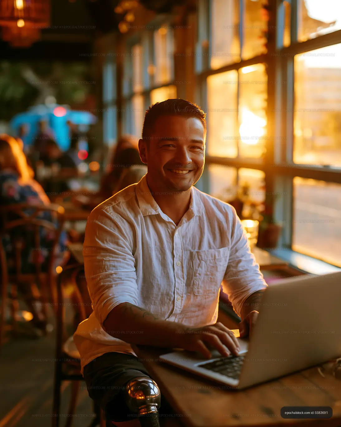 Happy man with laptop in warm cafe light