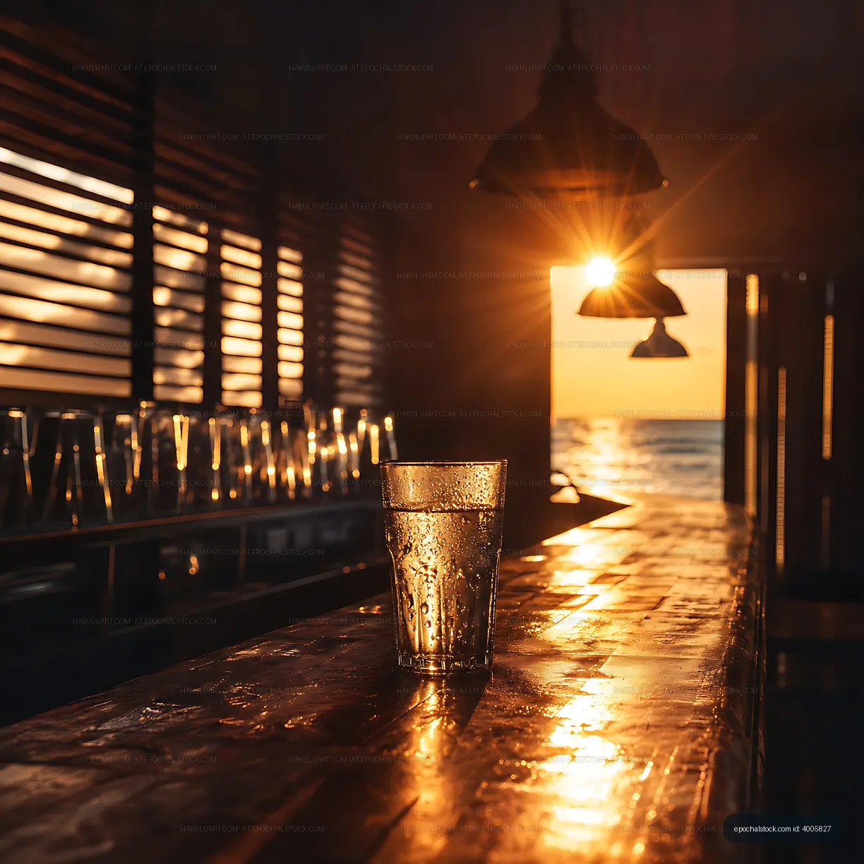 Glass of water at sunset on a wooden bar by the sea