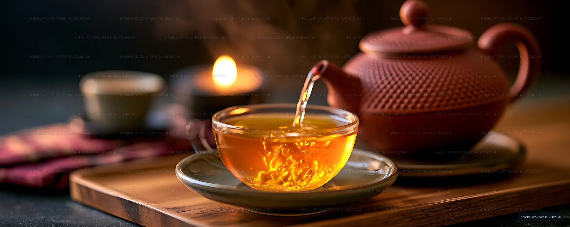Amber tea being poured from a teapot into a glass cup