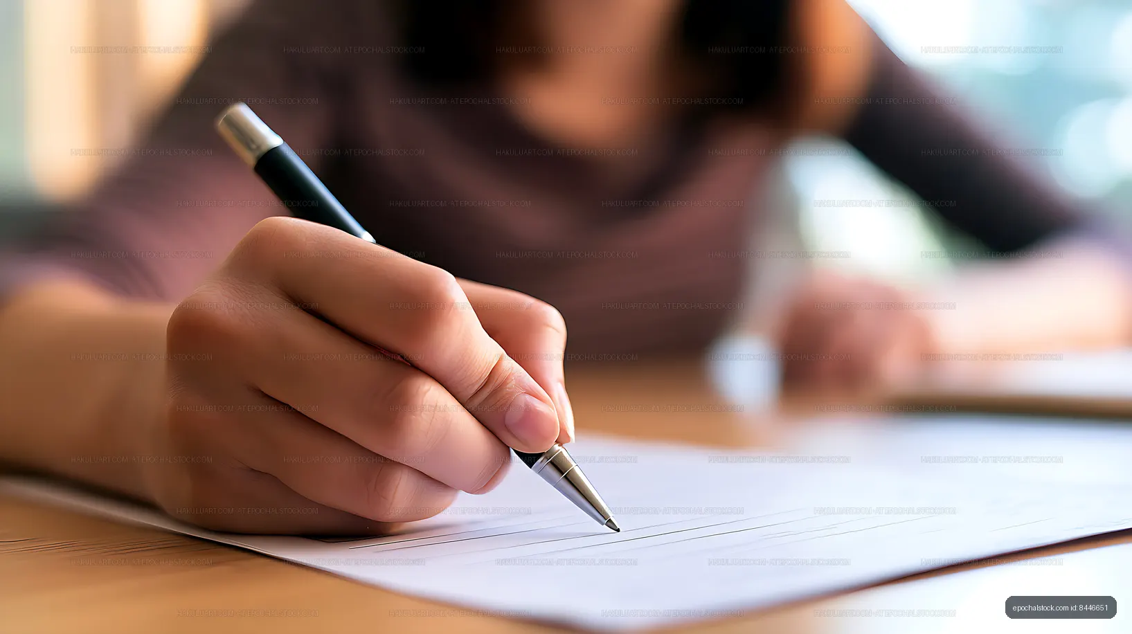 Person writing on paper at a desk