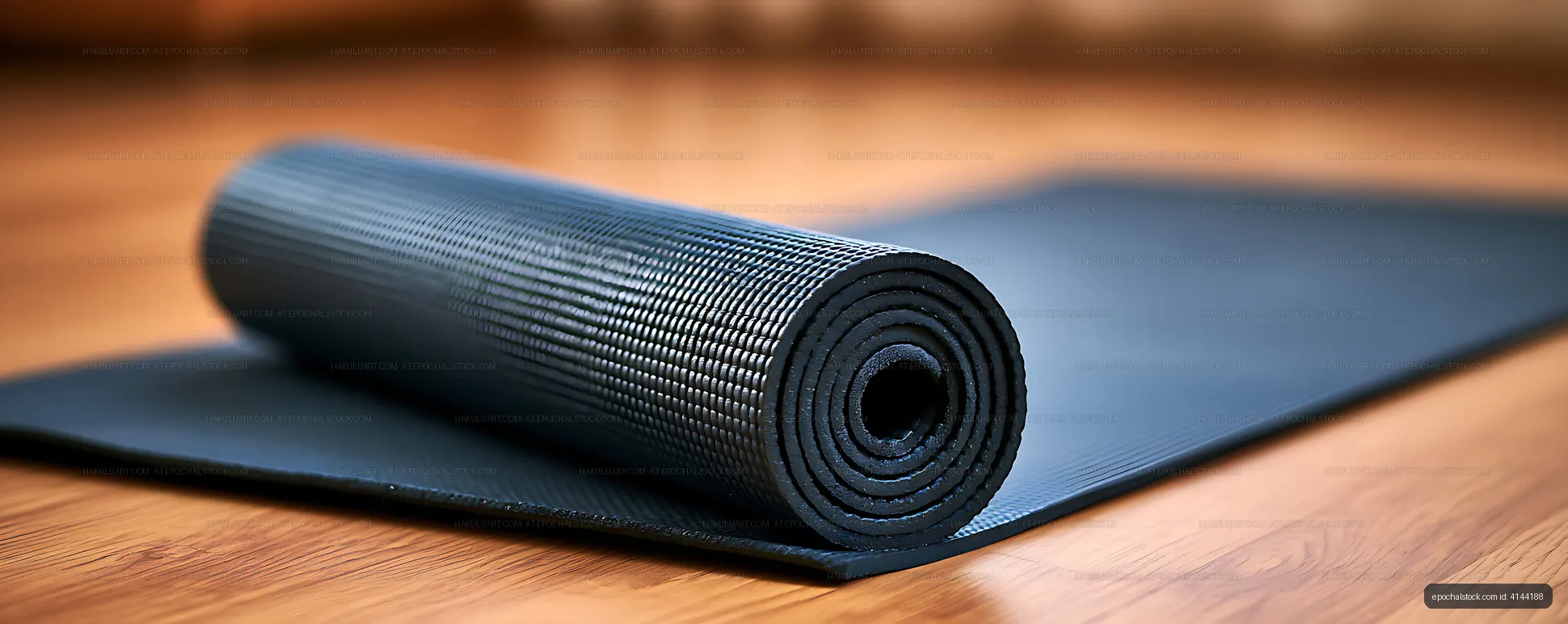 Textured black exercise mat rolled on a wooden floor